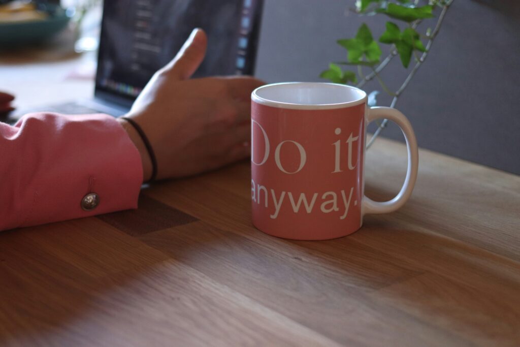 woman with laptop and mug of coffee writting intentional goals for 2025